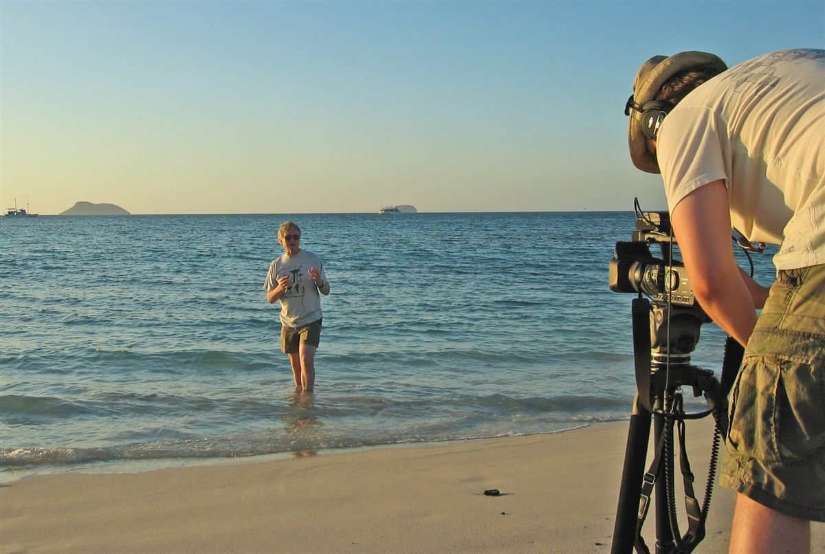 Josh filming Richard Dawkins on a beach in the Galápagos Islands